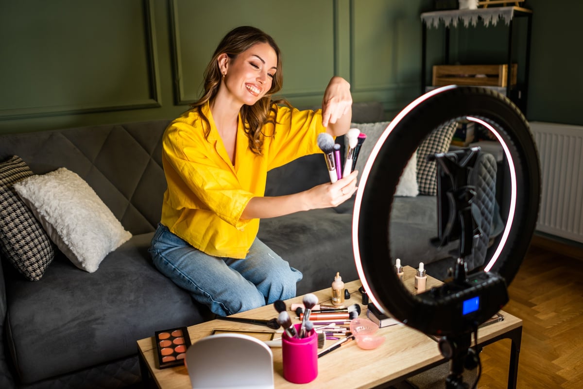 Influencer recording a beauty routine at home. She is using ring light and smartphone.