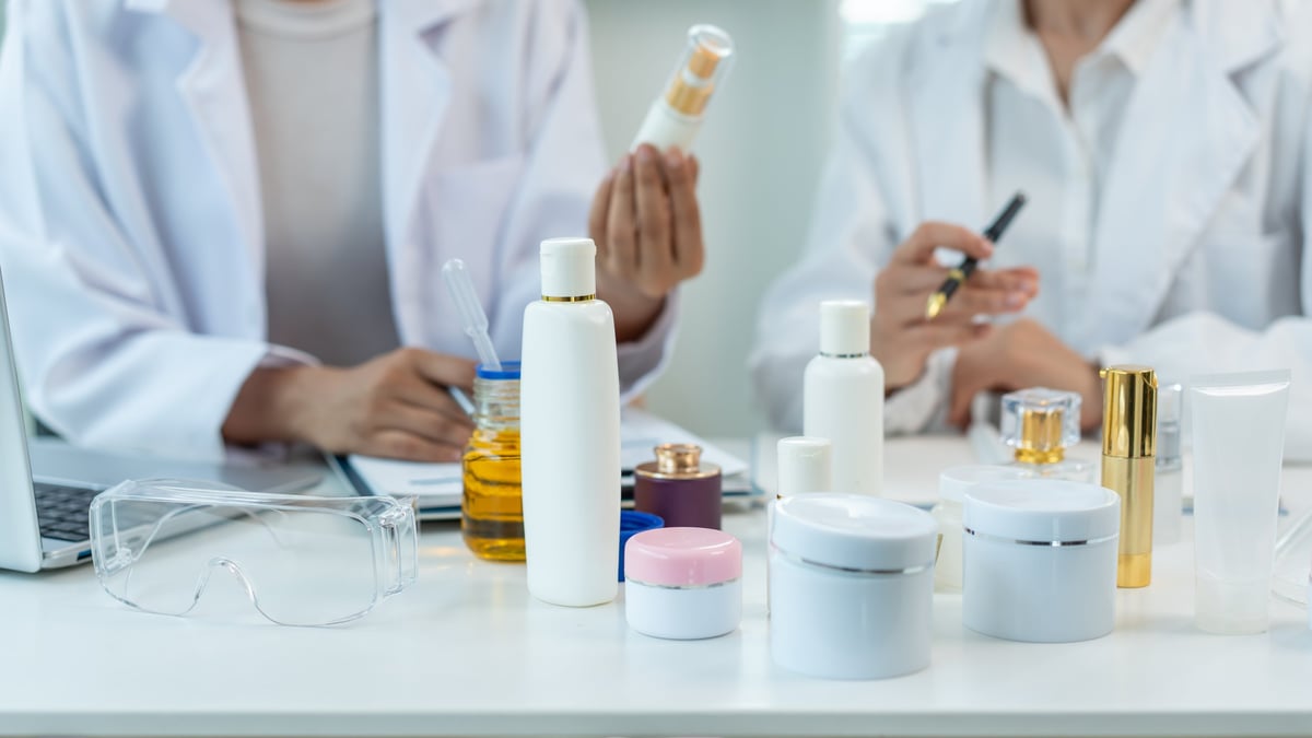 Equipo de científicos revisando envases de cosmética sobre una mesa blanca