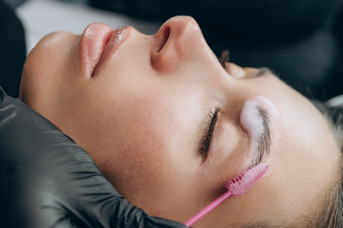 Especialista aplicando un tratamiento profesional de cejas con cepillo
